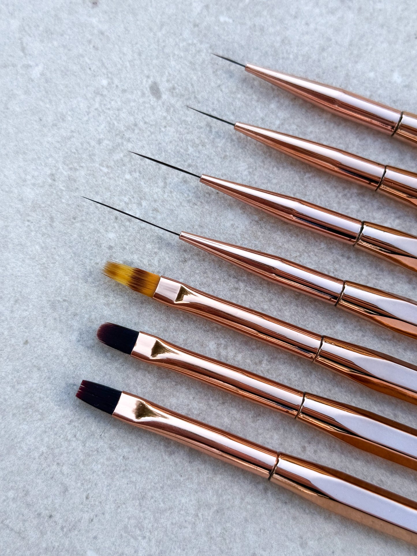 Sju stycken penslar för naglar till olika användningsområden i roséguldig färg.