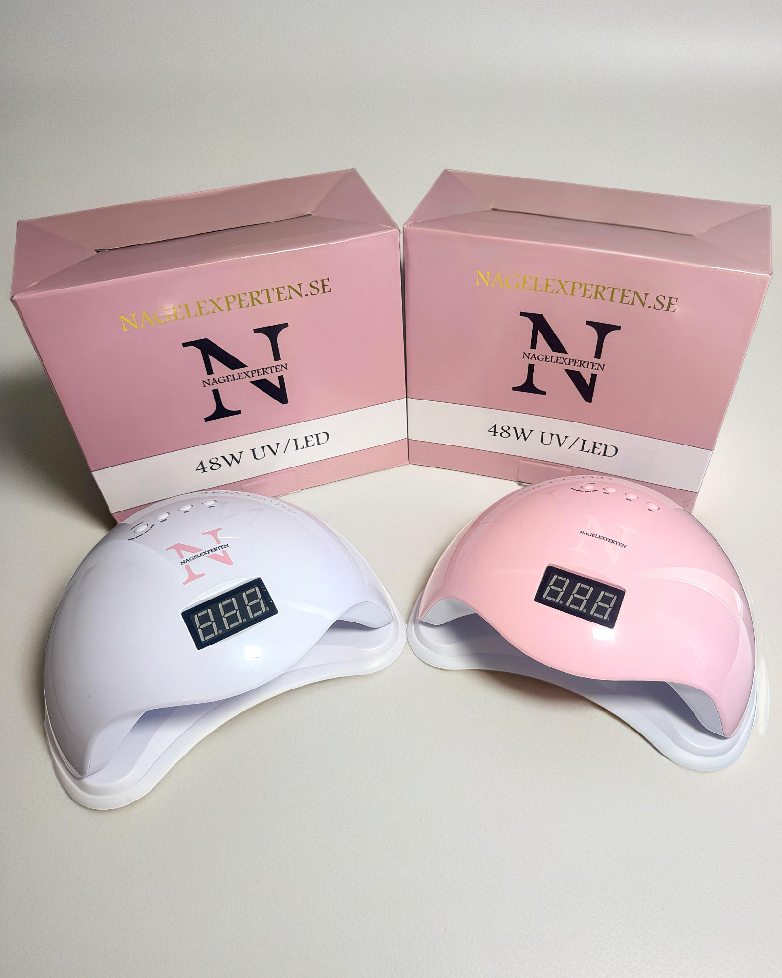 Två uv lampor i rosa och vit färg med tillhörande kartonger från Nagelexperten - För härdning av nagelprodukter.