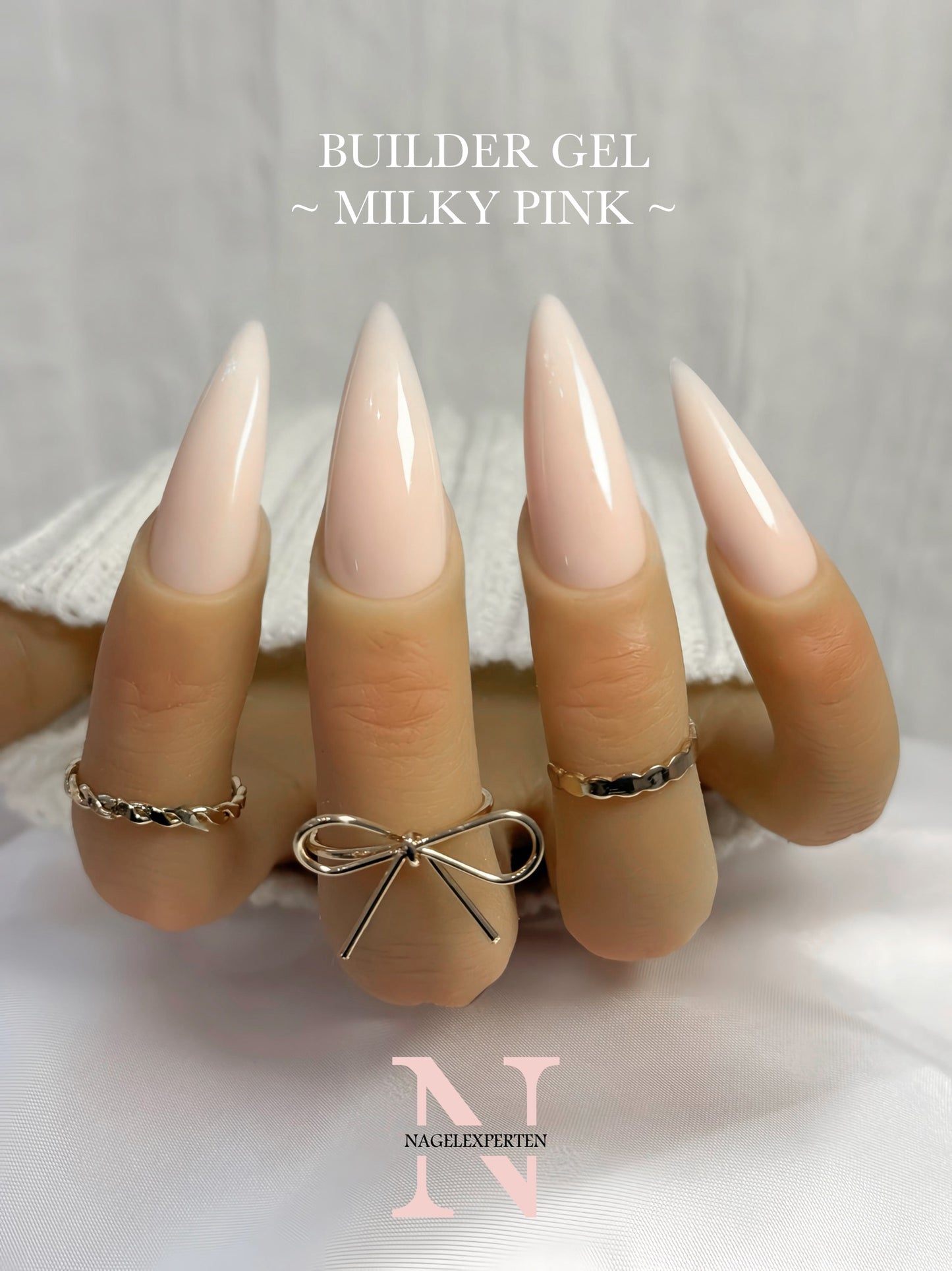 Hand med långa naglar målade med ljusrosa builder gel i färgen milky pink.