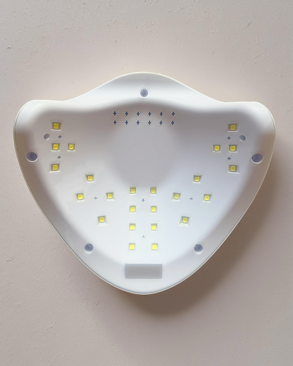 Nagellampa som ligger upp och ner på ett bord med 24 24 dioder för härdning av naglar.