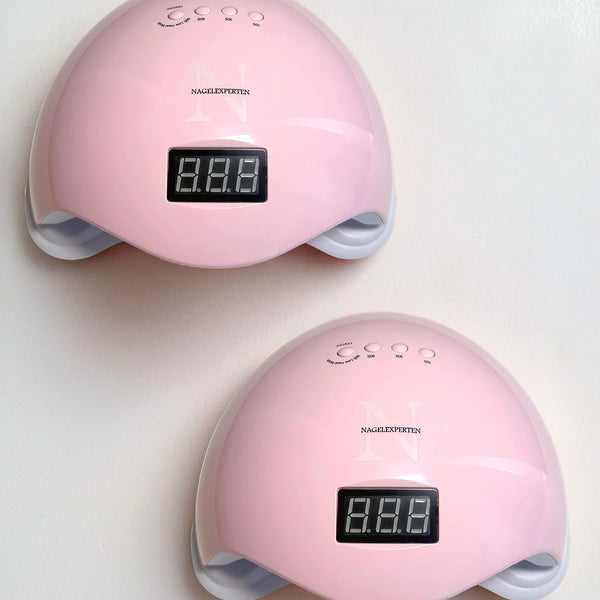 Två rosa uv-lampor från Nagelexperten som står på ett vitt bord.