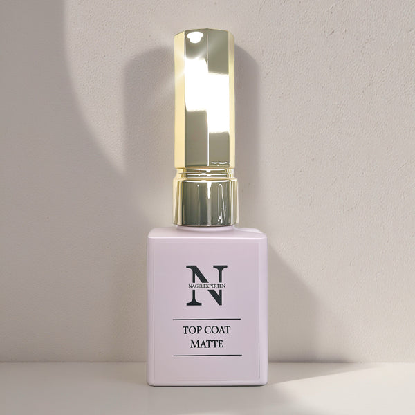 Top coat i lila guldig flaska som ger en matt design till naglar.